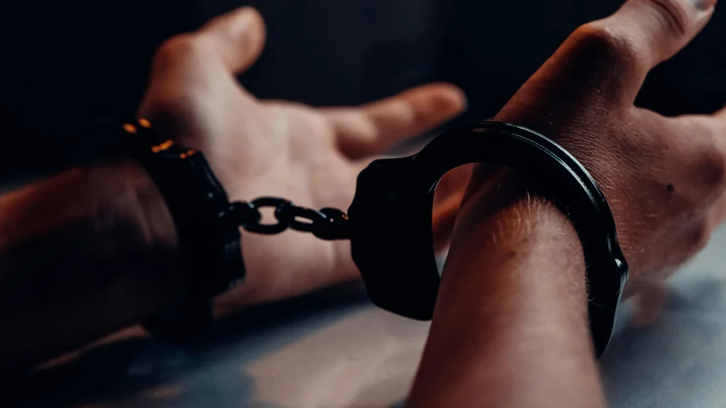 Close-up of a person in handcuffs with hands restrained behind their back.