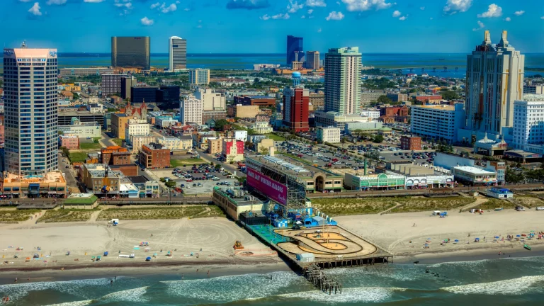 Aerial view of a beachfront city skyline with high-rise buildings, casinos, and a pier along the shore.
