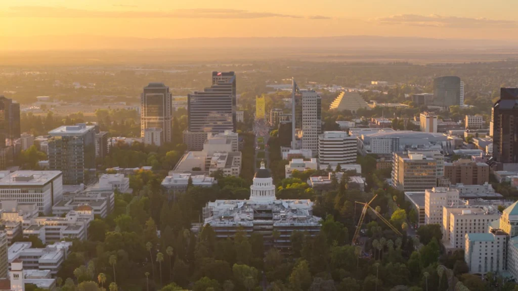Aerial view of a state capitol building and downtown skyline at sunset.