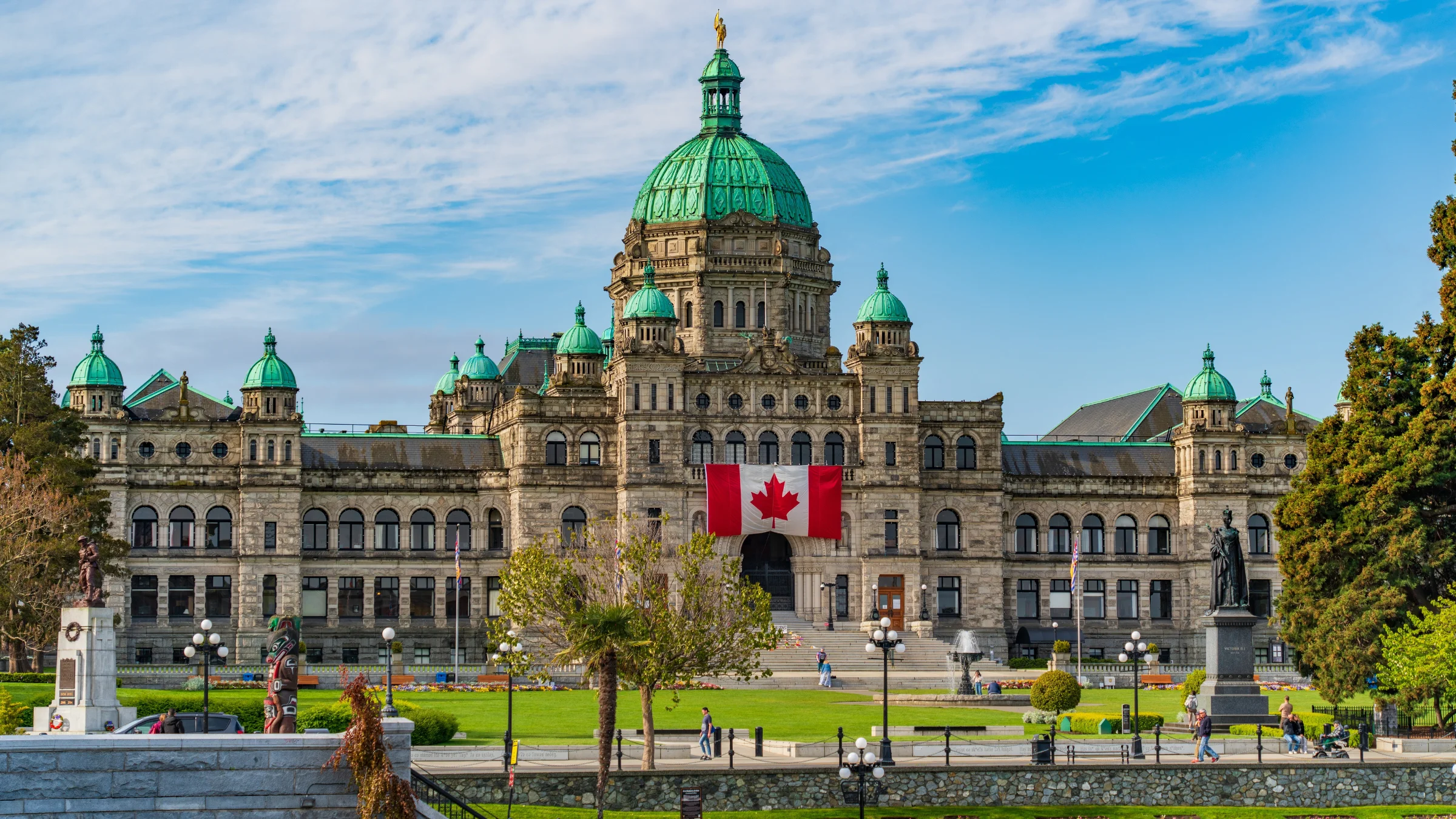Historic parliament building with green domes and a Canadian flag displayed at the front.