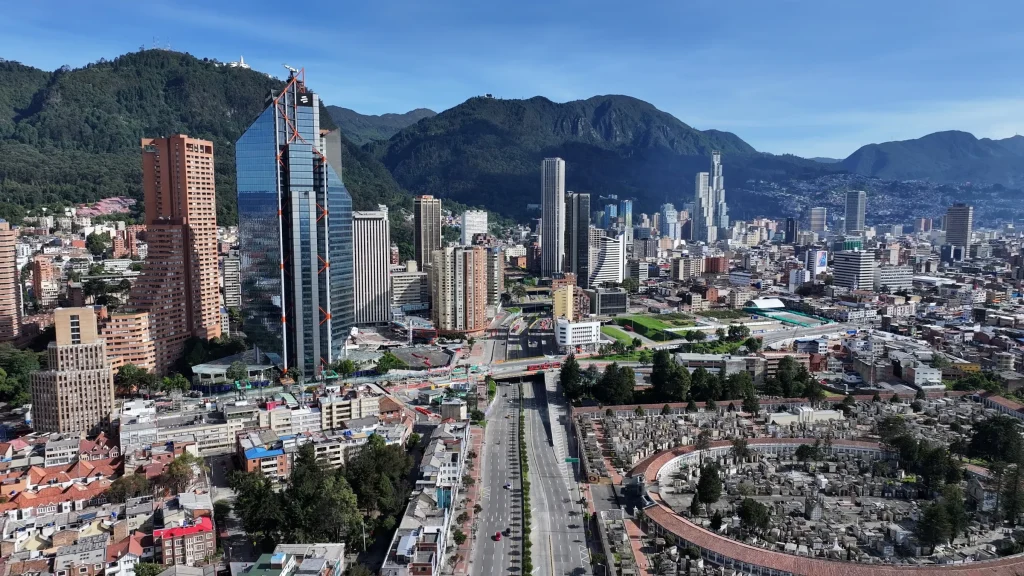 Aerial view of a dense city skyline framed by mountains and major roads.