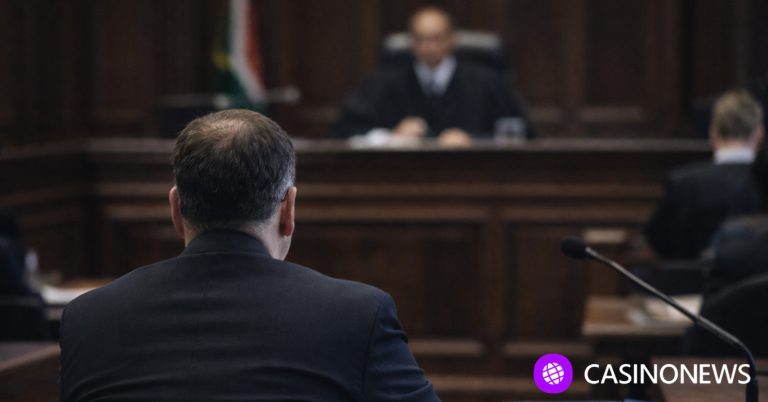 Man seated at a courtroom hearing facing a judge, representing the Investec R2.6 million online gambling debt case.