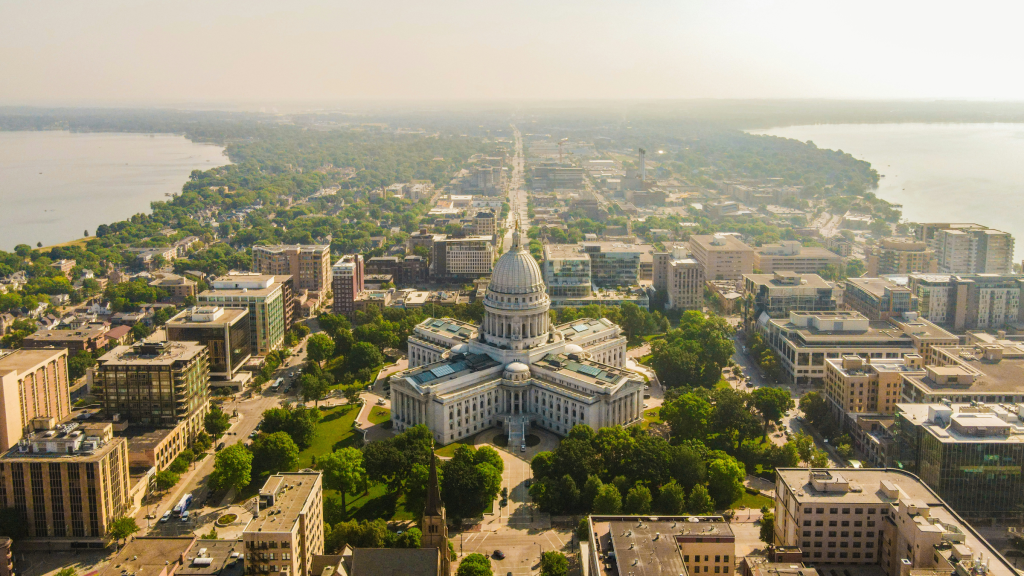 Aerial view of a domed state capitol building surrounded by city streets and lakes.