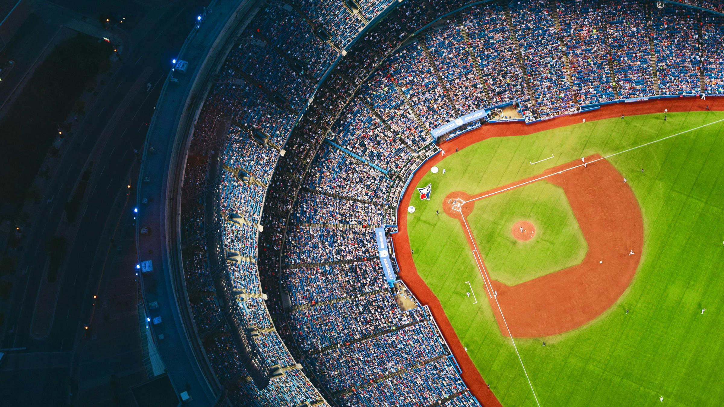 Aerial view of a baseball stadium packed with fans during a live game at night.