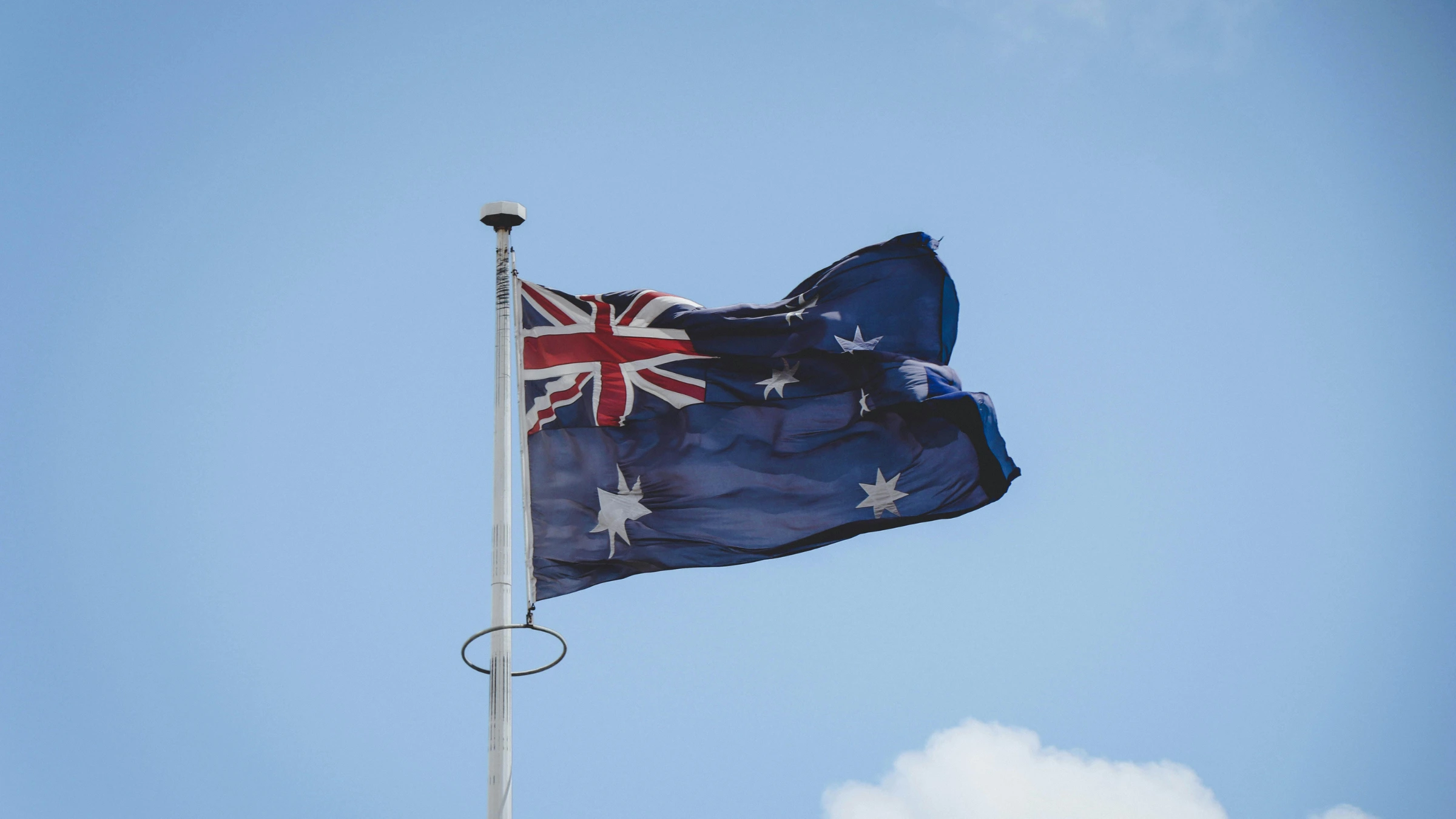 Australian flag waving on a flagpole against a clear blue sky