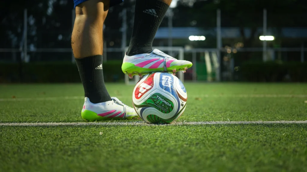 Football player places boot on soccer ball during training session on grass field