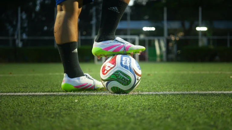 Football player places boot on soccer ball during training session on grass field