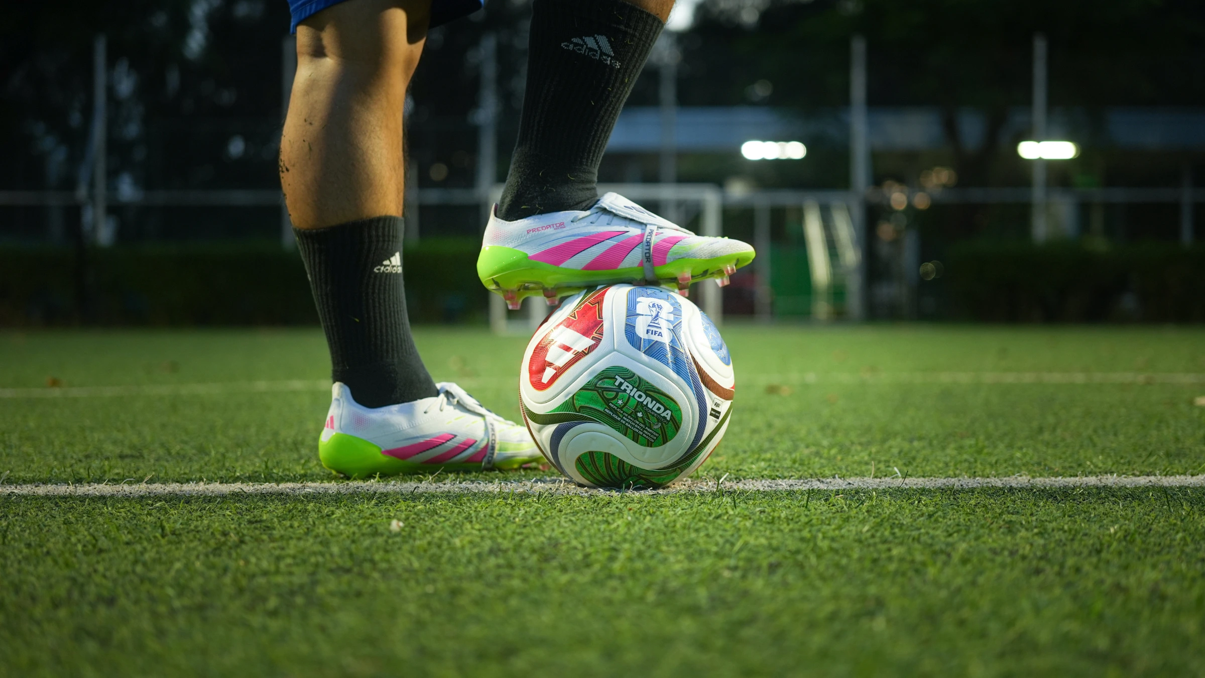 Football player places boot on soccer ball during training session on grass field