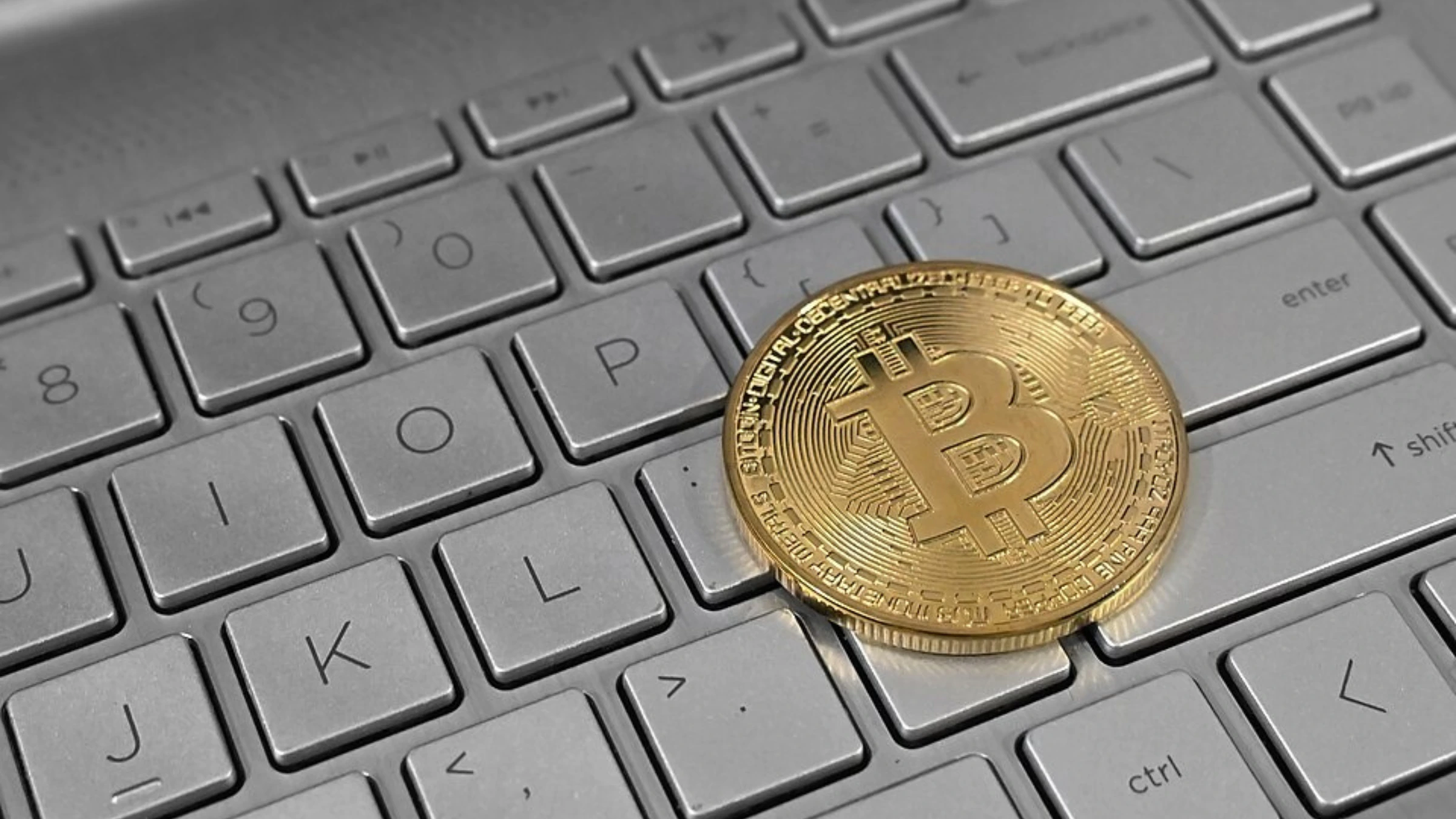 Bitcoin cryptocurrency coin resting on computer keyboard representing digital asset trading