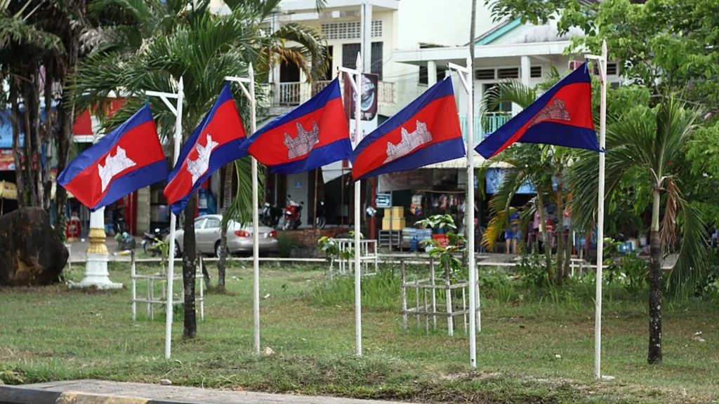 Multiple Cambodian national flags displayed along a landscaped urban street