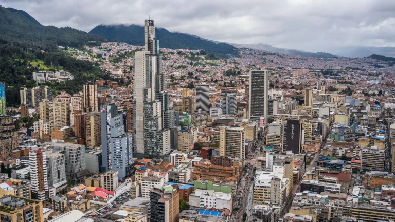 Aerial view of Bogotá skyline with high-rise buildings and mountains under cloudy skies
