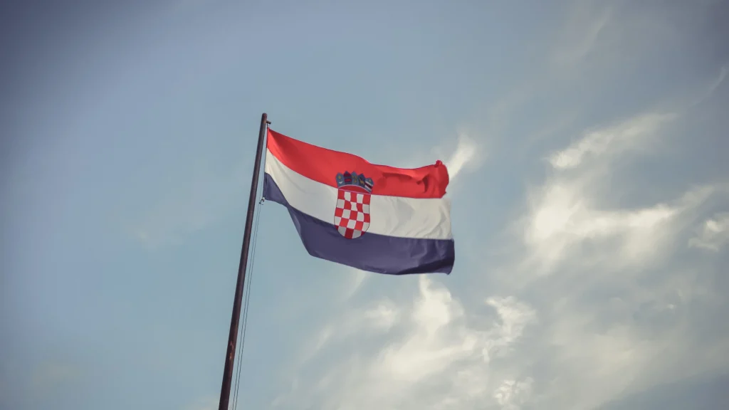 Croatian national flag flying on flagpole beneath cloudy sky