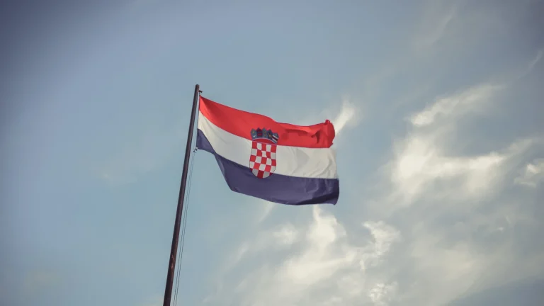 Croatian national flag flying on flagpole beneath cloudy sky