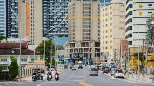 Urban street lined with high-rise buildings, traffic, and mixed commercial development in a dense city district.