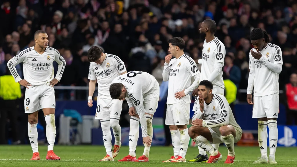 Real Madrid players react on the pitch after a setback during a night match.