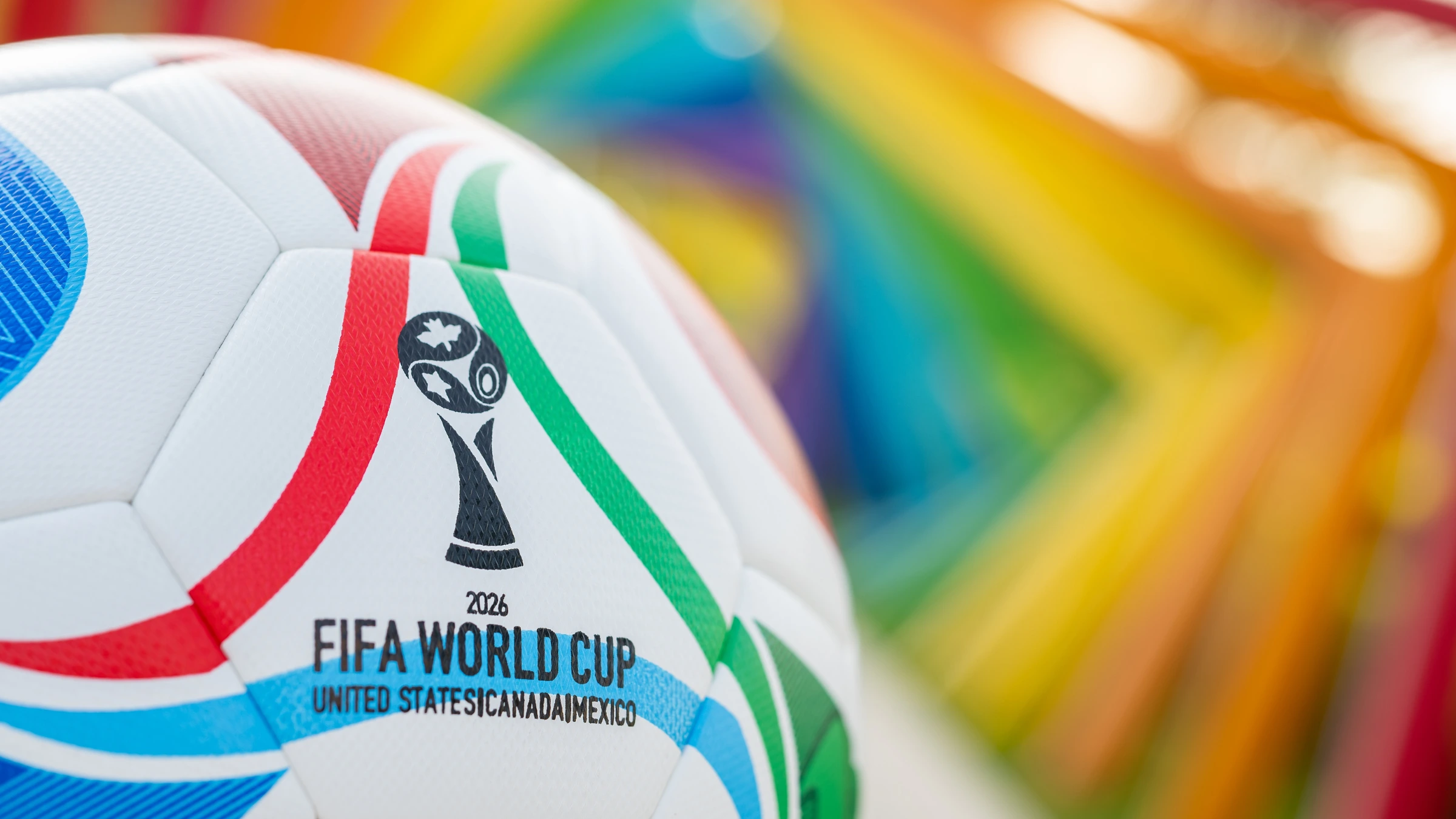 FIFA World Cup 2026 match ball with colorful stadium seats background