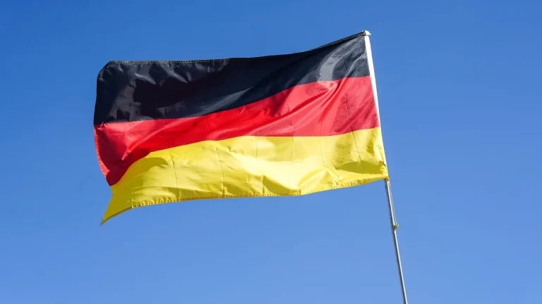 German national flag waving against a clear blue sky representing Germany’s regulatory environment