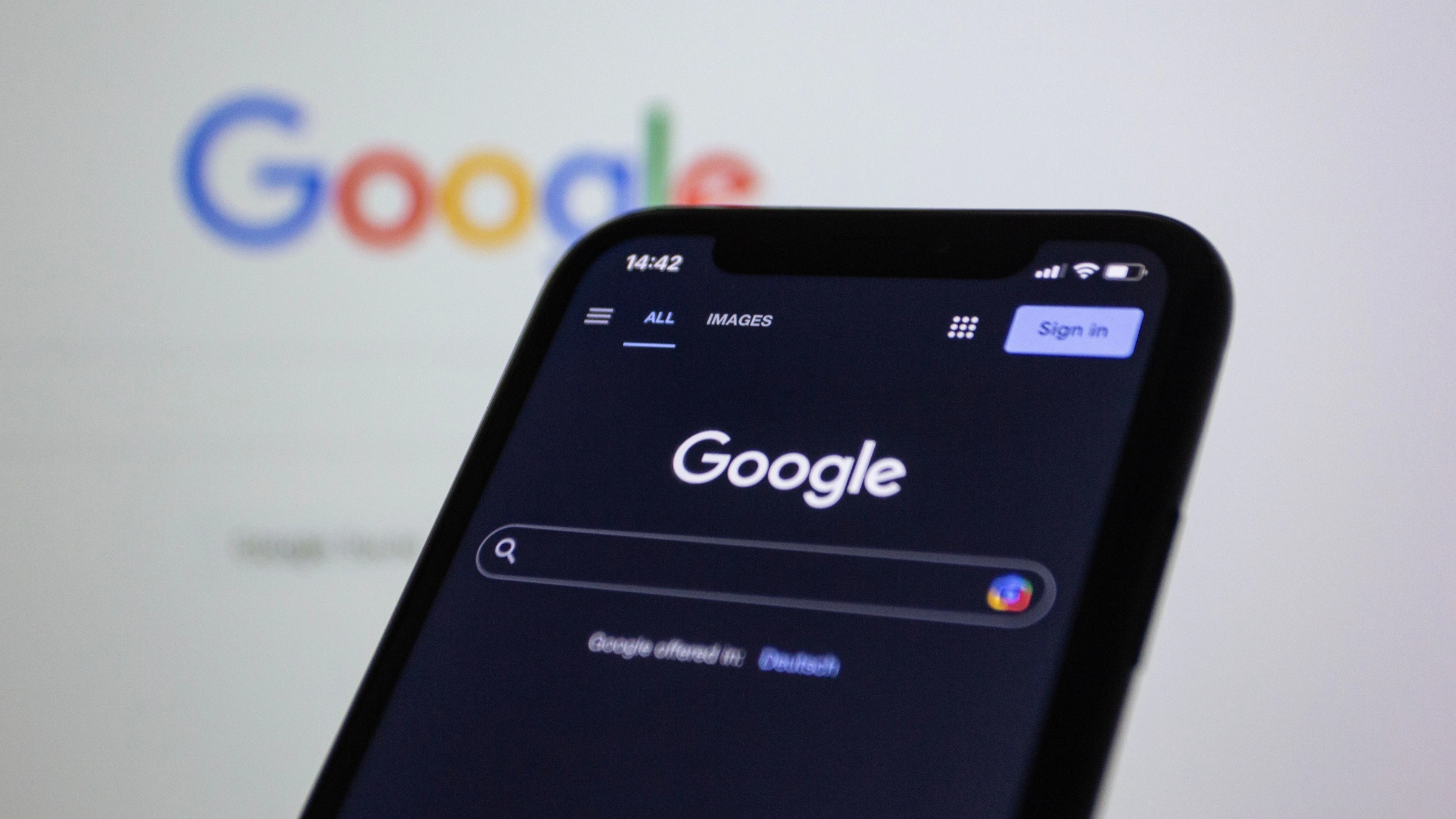Google search page shown on mobile device against blurred company logo