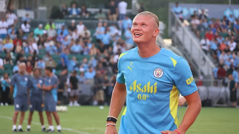 Professional football striker during training session with supporters in the background