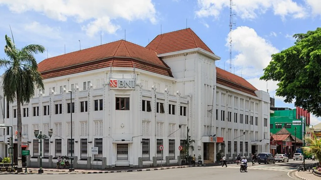 Large white colonial-style building with red roof and BNI sign at busy street intersection.