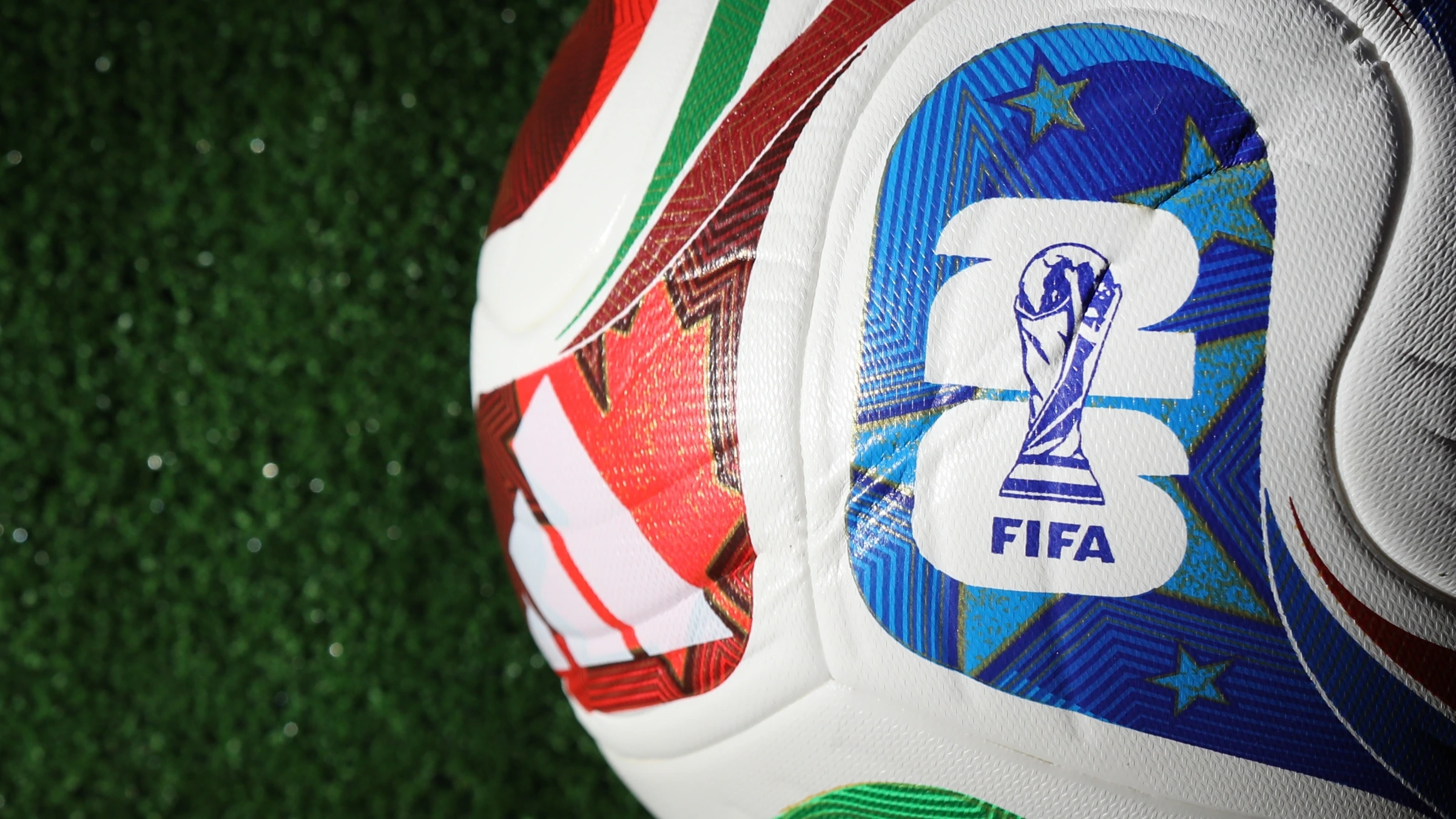 Close-up of FIFA branded football resting on artificial grass surface
