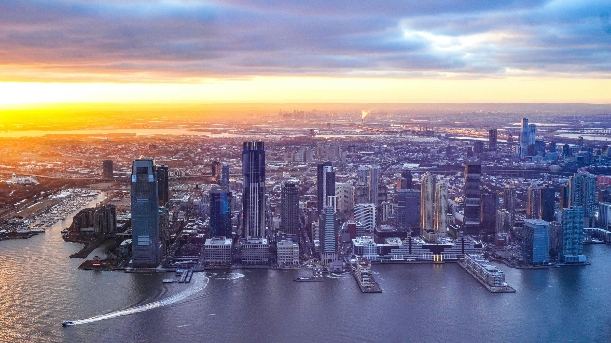 City skyline at sunset with waterfront and high-rise buildings.