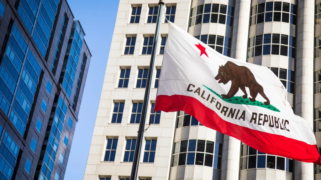California state flag flying between modern office buildings in downtown business district