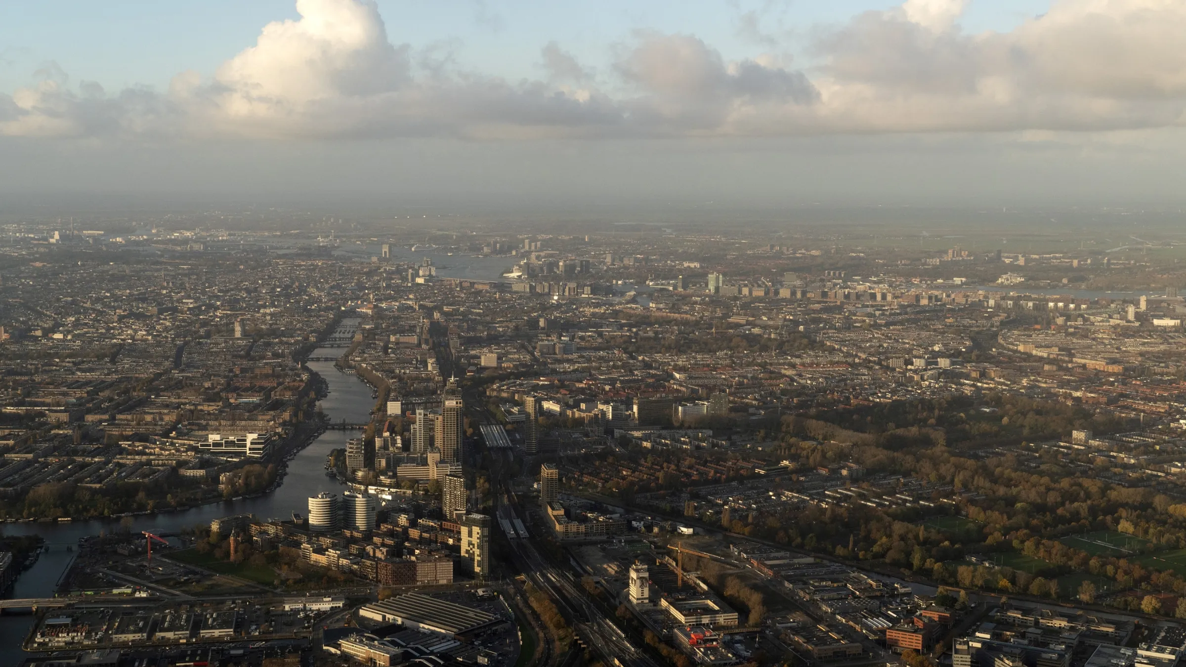 Aerial view of Amsterdam metropolitan area with canals, residential districts and cloudy skyline