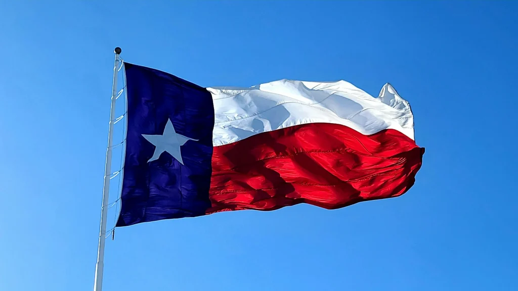 Texas state flag waving against a bright blue sky