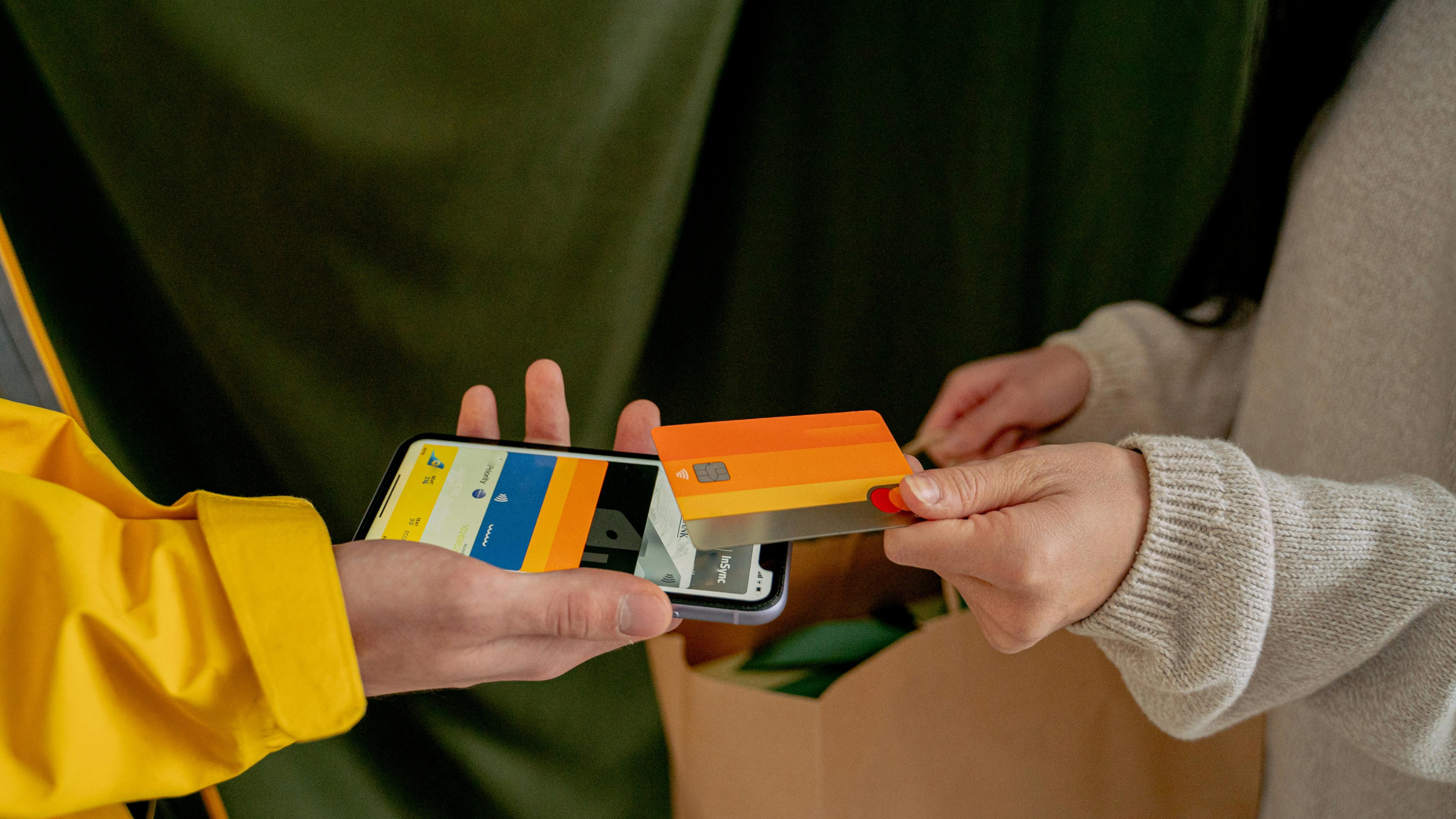 Customer handing a payment card to a courier holding a mobile payment device and package.