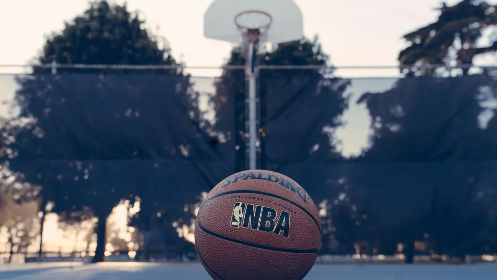 NBA basketball resting on outdoor court with hoop blurred in background