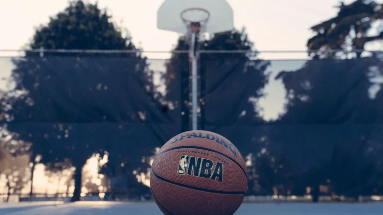NBA basketball resting on outdoor court with hoop blurred in background