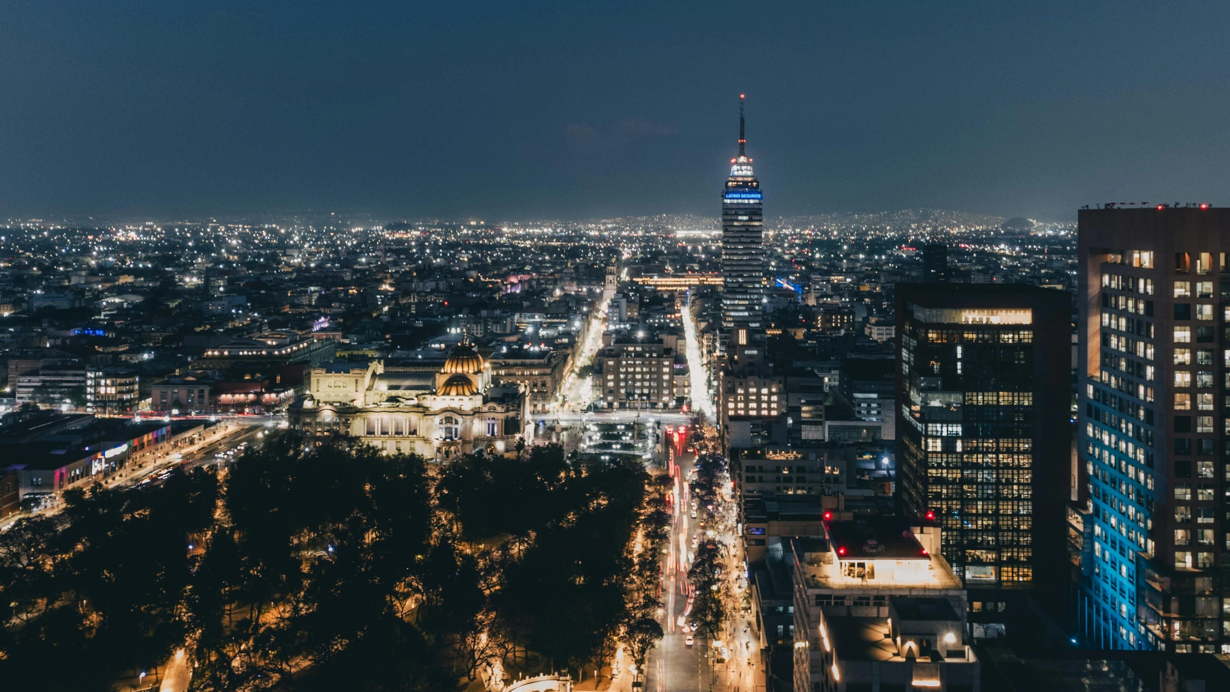 Nighttime skyline of Mexico City with illuminated skyscrapers and city lights