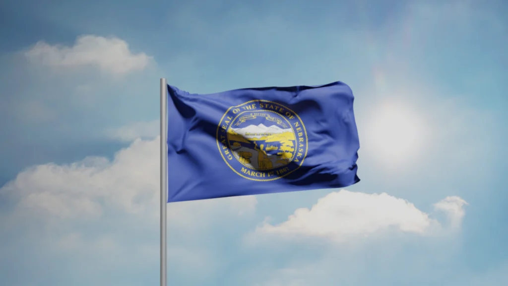 Nebraska state flag waving against a bright blue sky