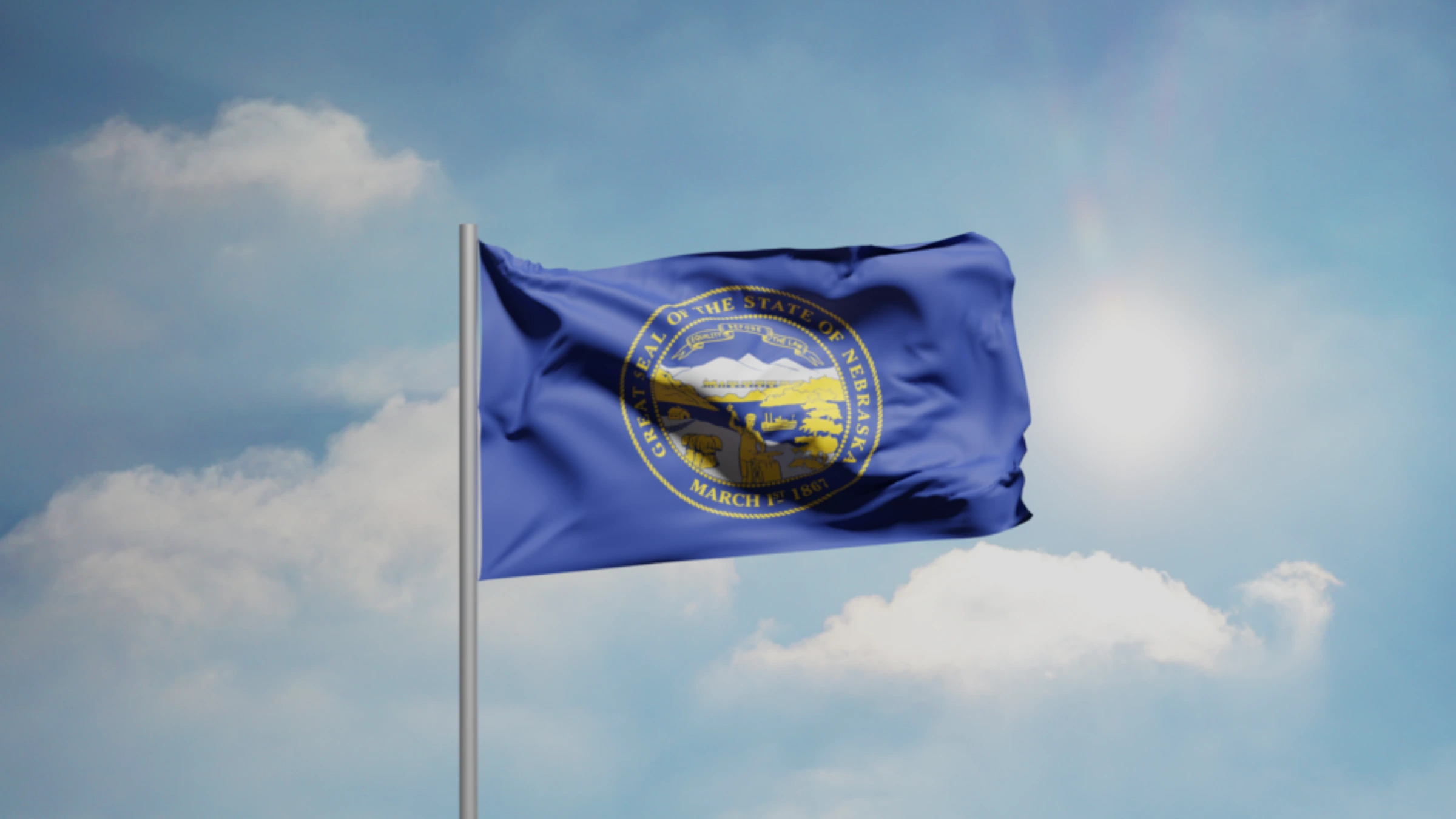Nebraska state flag waving against a bright blue sky