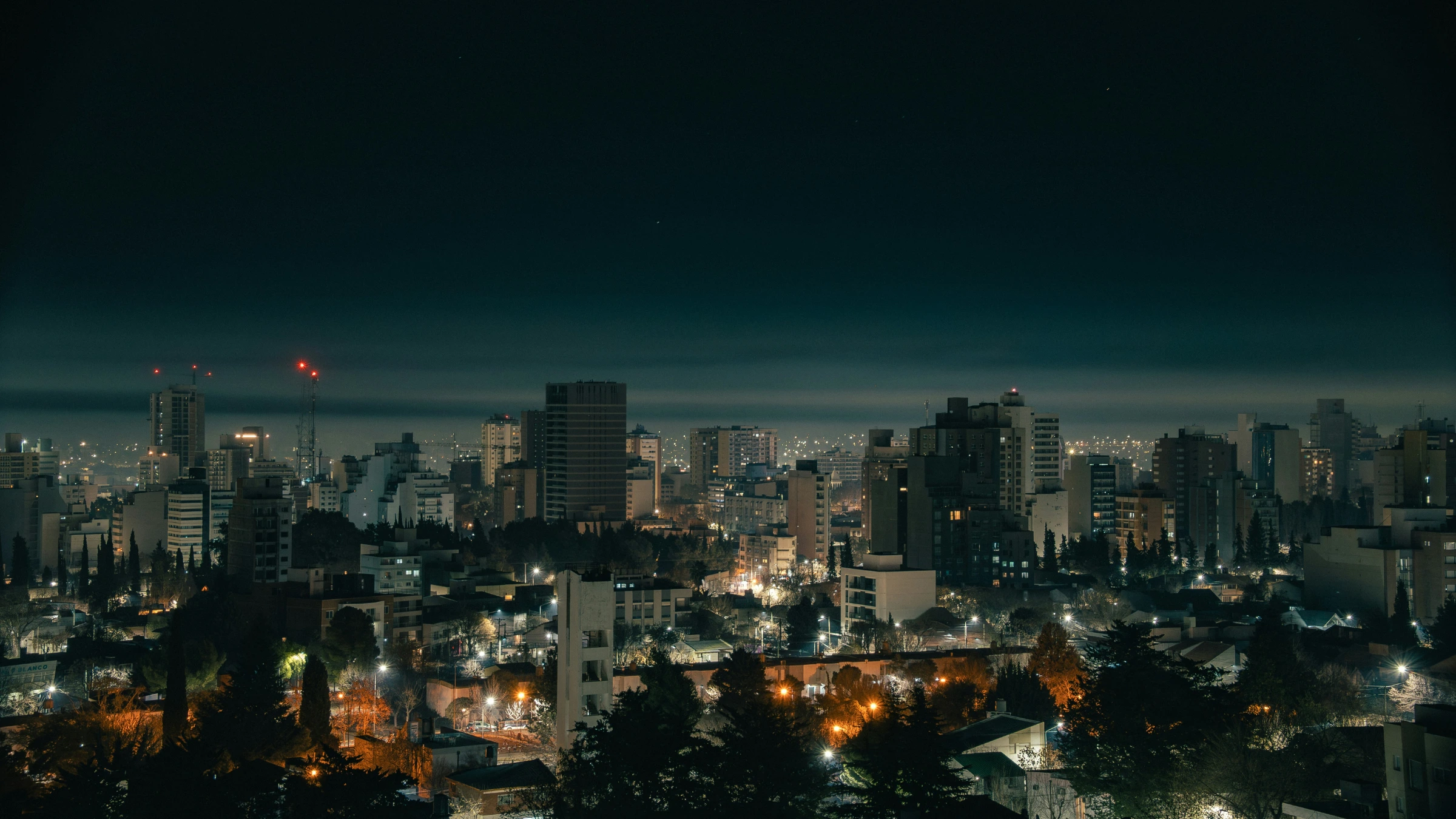 Nighttime skyline of Neuquén city with illuminated buildings and urban streets in Argentina