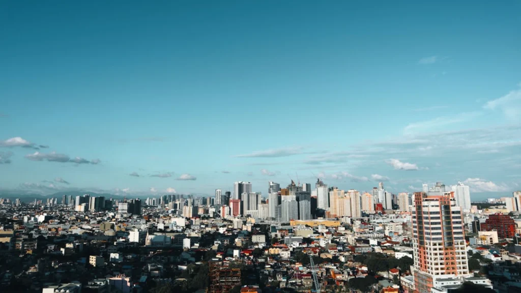 Wide city skyline with dense buildings under blue sky and scattered clouds.