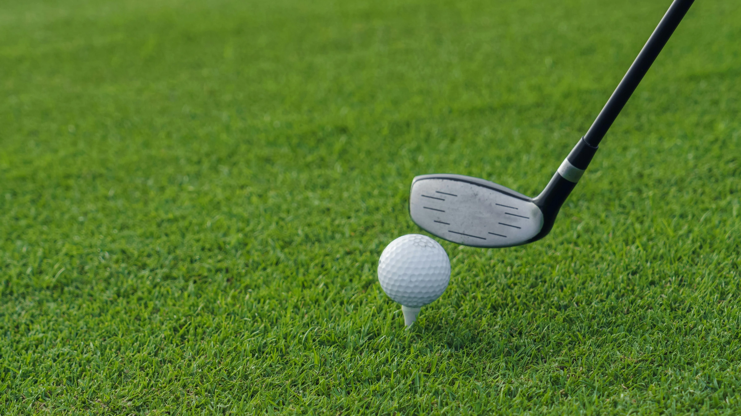 Golf club positioned behind ball on tee before drive shot