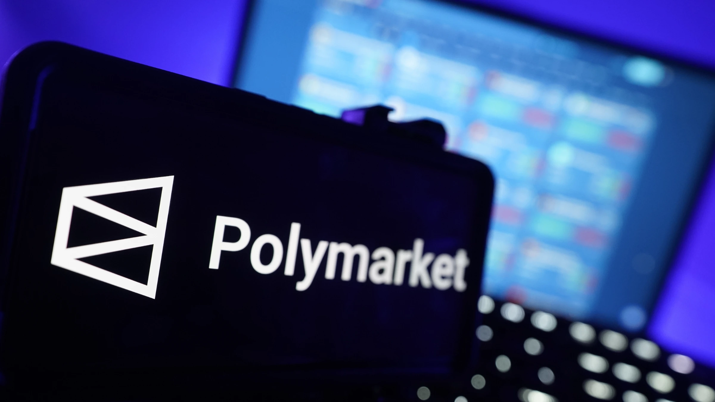 Polymarket logo shown on mobile device with trading platform visible behind