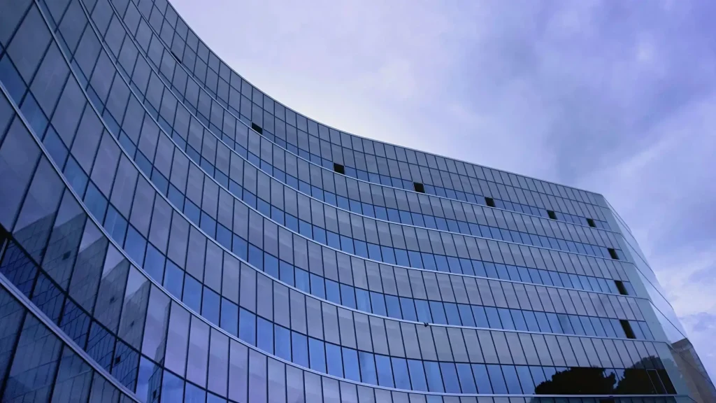 Modern glass office building exterior under cloudy sky