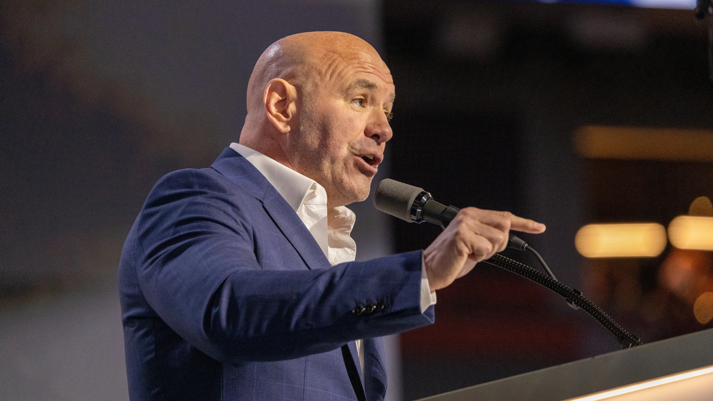 Dana White speaking at podium alongside sports betting industry graphics