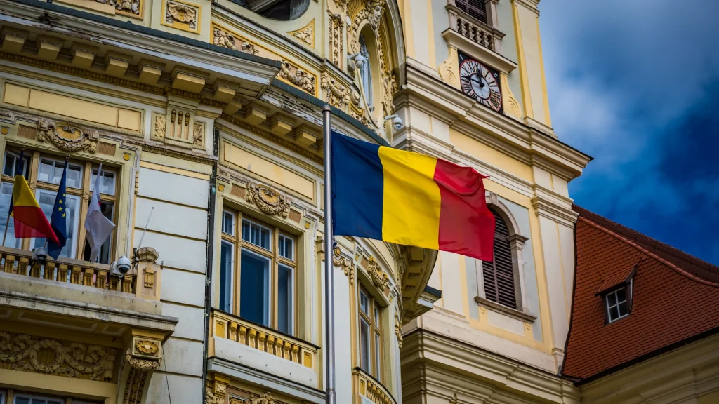 Romanian flag flying in front of an ornate historic government building