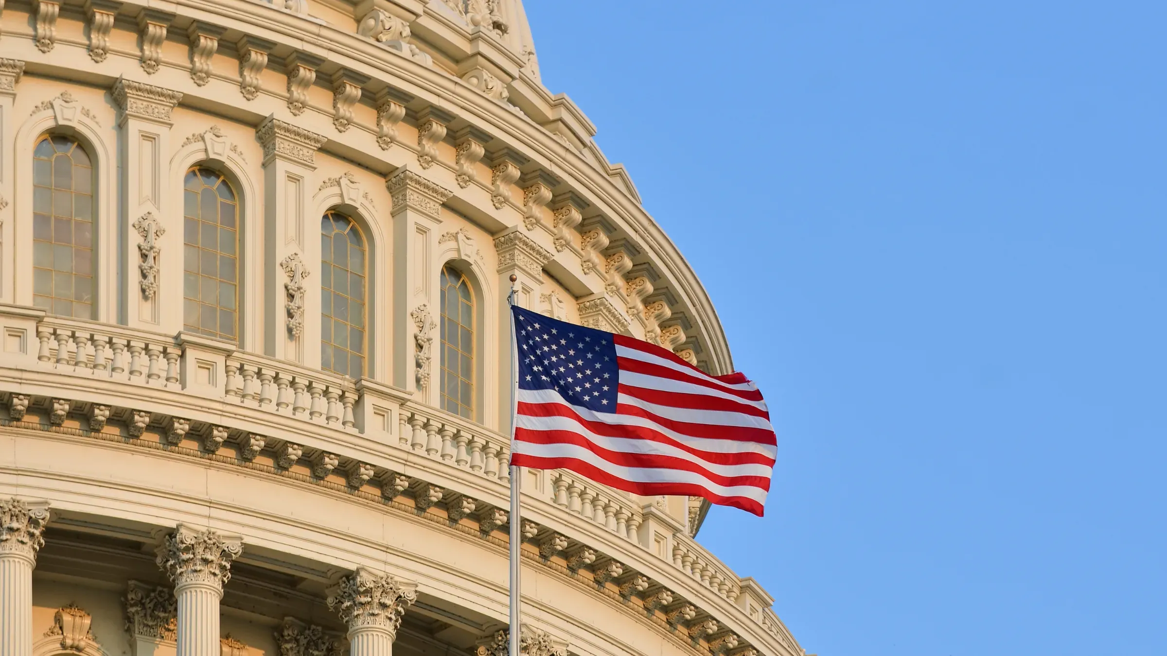 American flag flying near United States Capitol building under clear sky