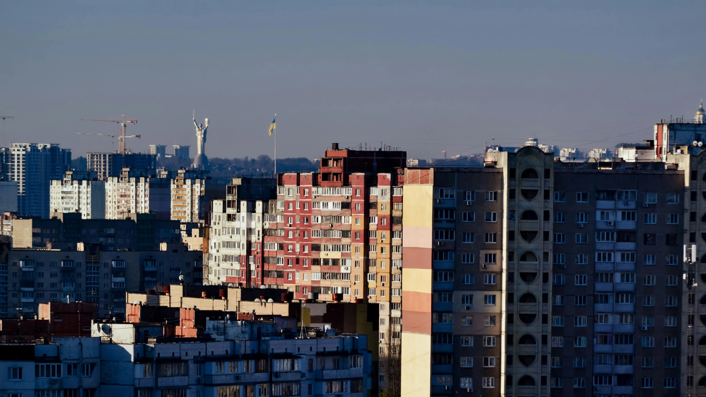 Kyiv residential skyline with Ukrainian flag visible in distance