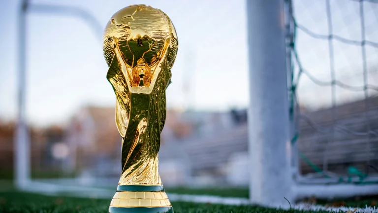 FIFA World Cup trophy displayed beside football goal on pitch