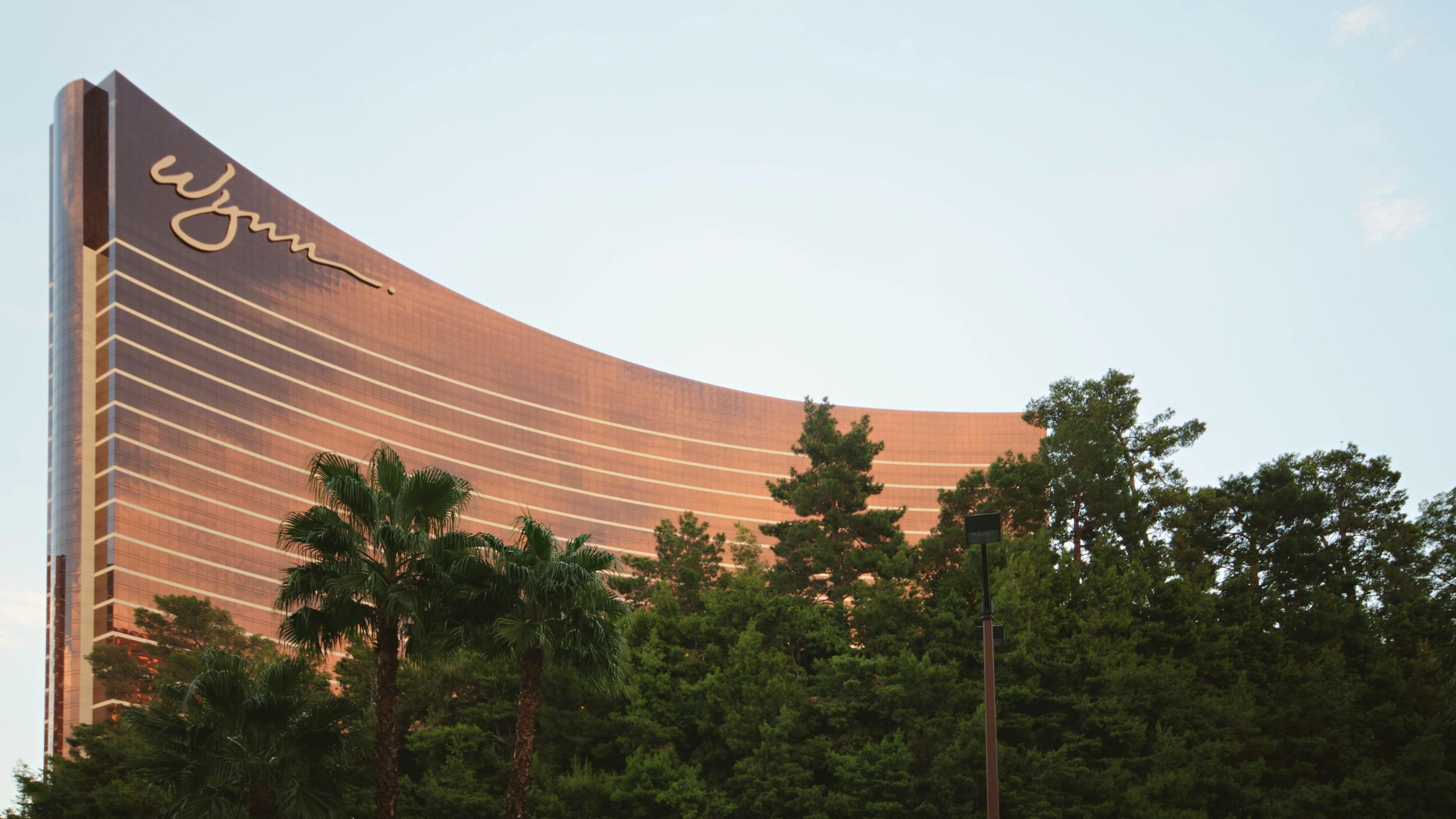 Wynn Las Vegas resort exterior with curved bronze tower and palm trees